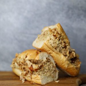 closeup shot of Chicken Cheesesteak kept on a wooden board with a gray background