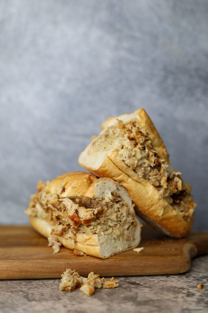 closeup shot of Chicken Cheesesteak kept on a wooden board with a gray background